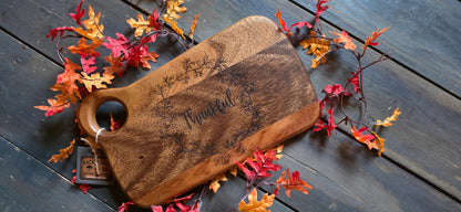 Wooden cutting board with 'Thankful' engraving on a wooden surface with autumn leaves.